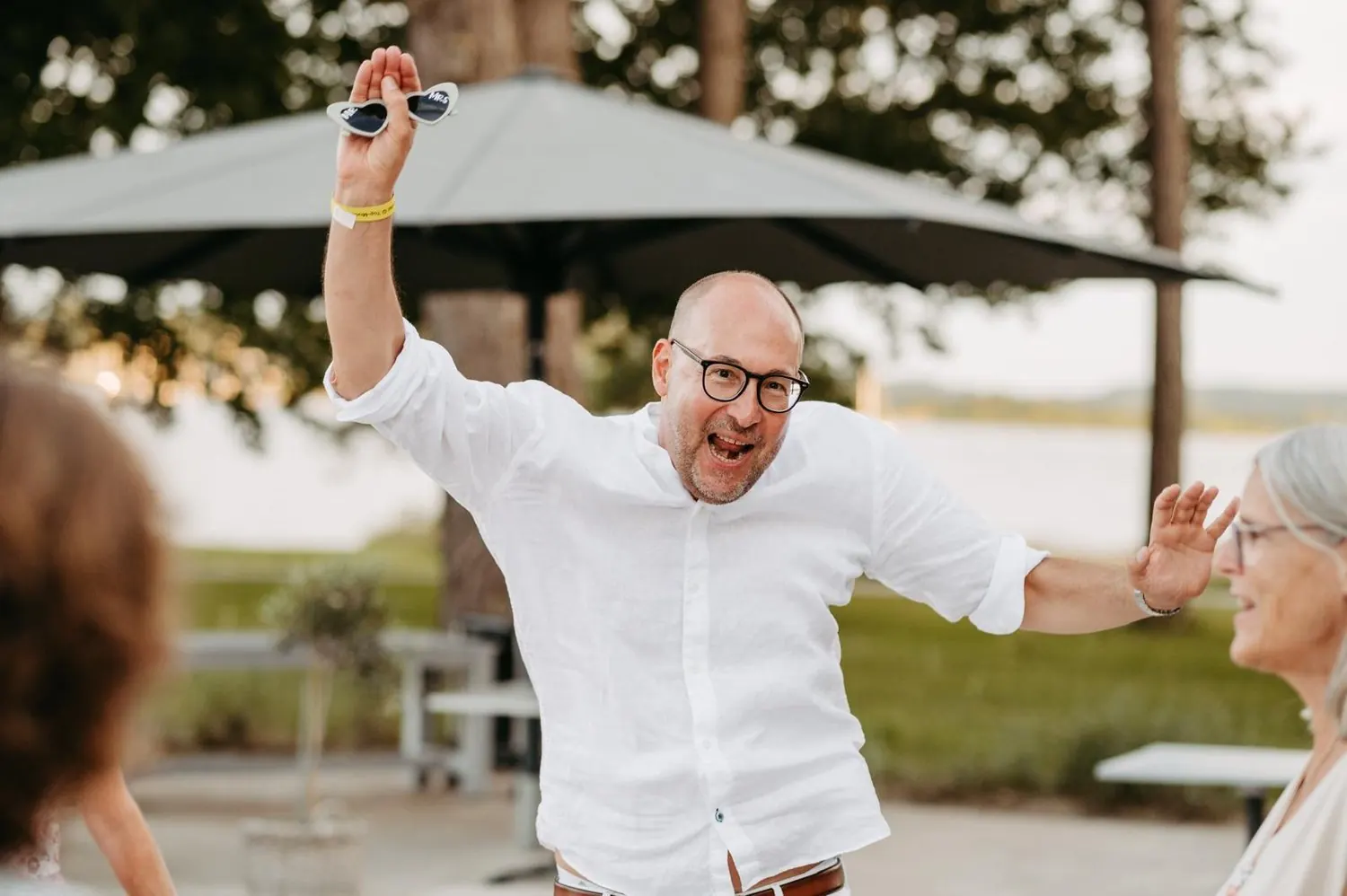 Ein Gast feiert ausgelassen mit Partybrille in der Hand