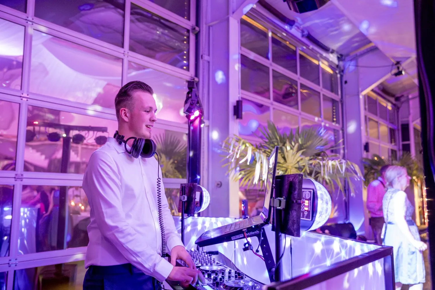 Saal in violettem Licht, im Vordergrund DJ Nick Baumgarten am DJ-Pult